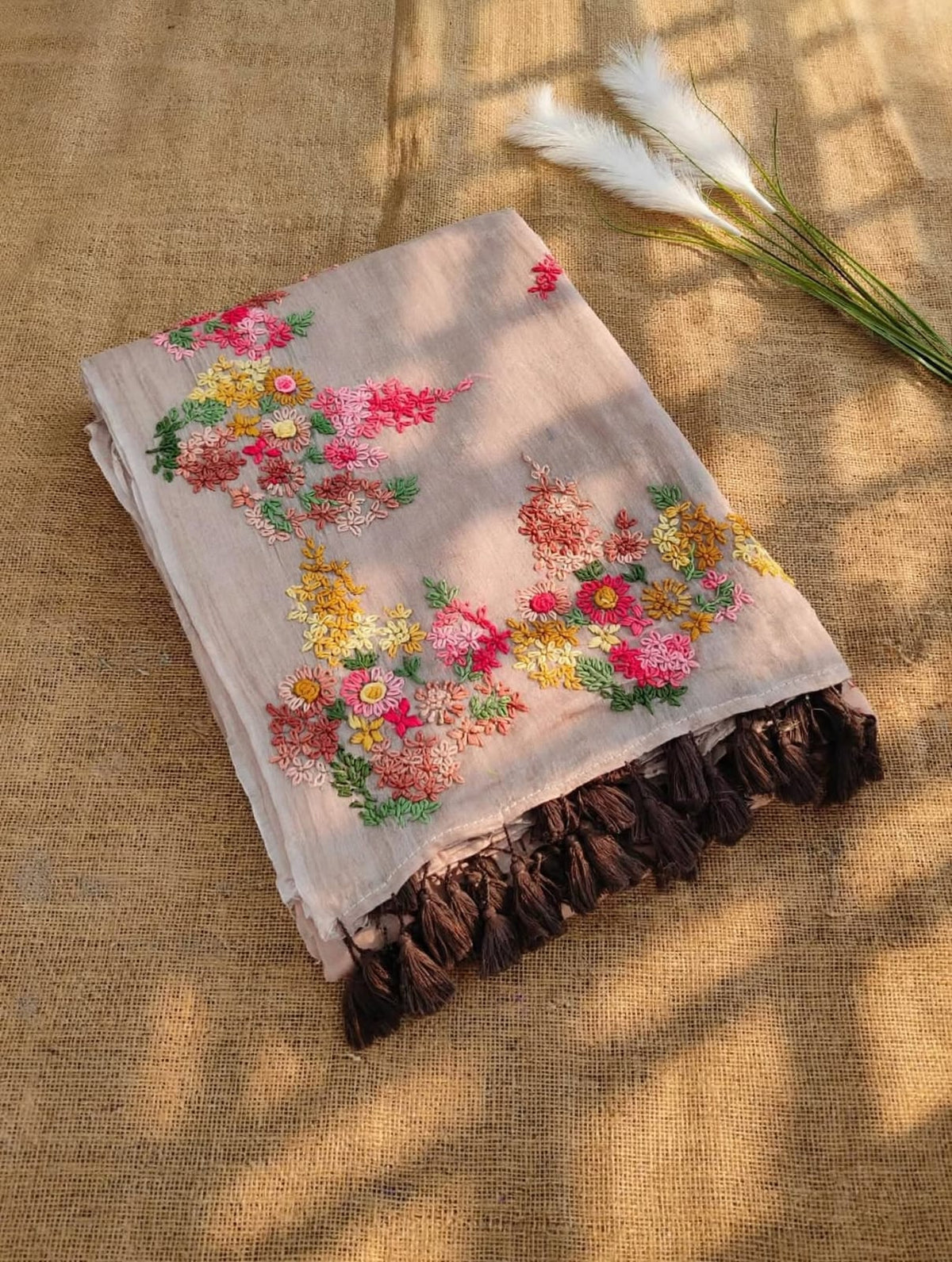 Taupe beige mul cotton saree with colourful floral embroidery and dark brown tassels