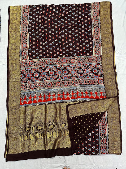 Deep brown Dola silk Ajrakh handblocked saree with small floral motifs, multicolour geometric pallu and antique gold border