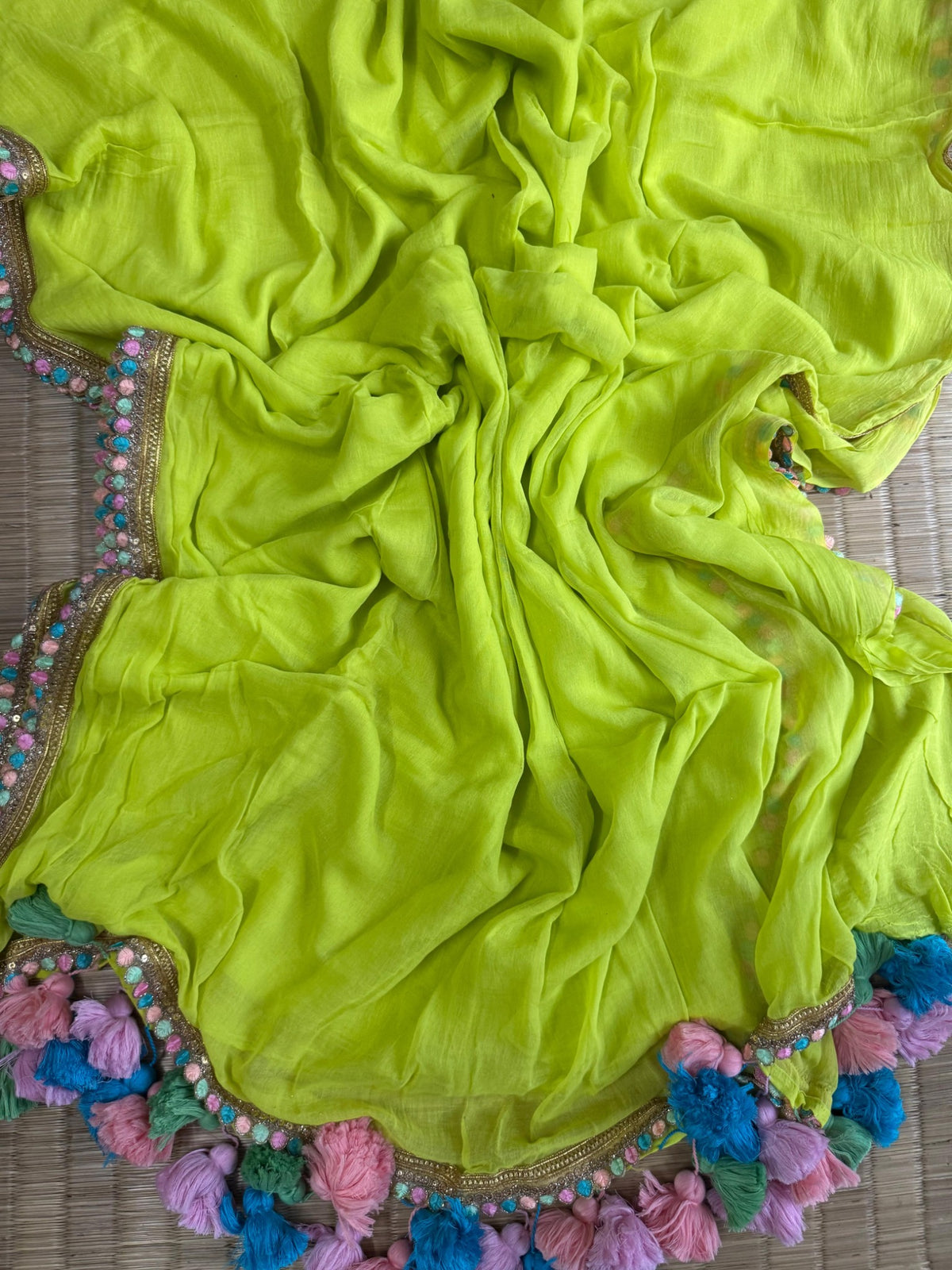 Lime green mul cotton saree with gold-toned embellished border and multicolour tassels