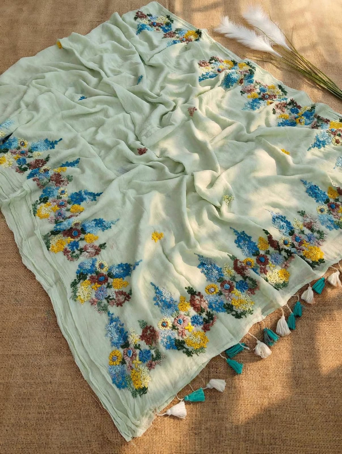 Mint green mul cotton saree with blue, yellow and multicolour floral embroidery and teal and ivory tassels