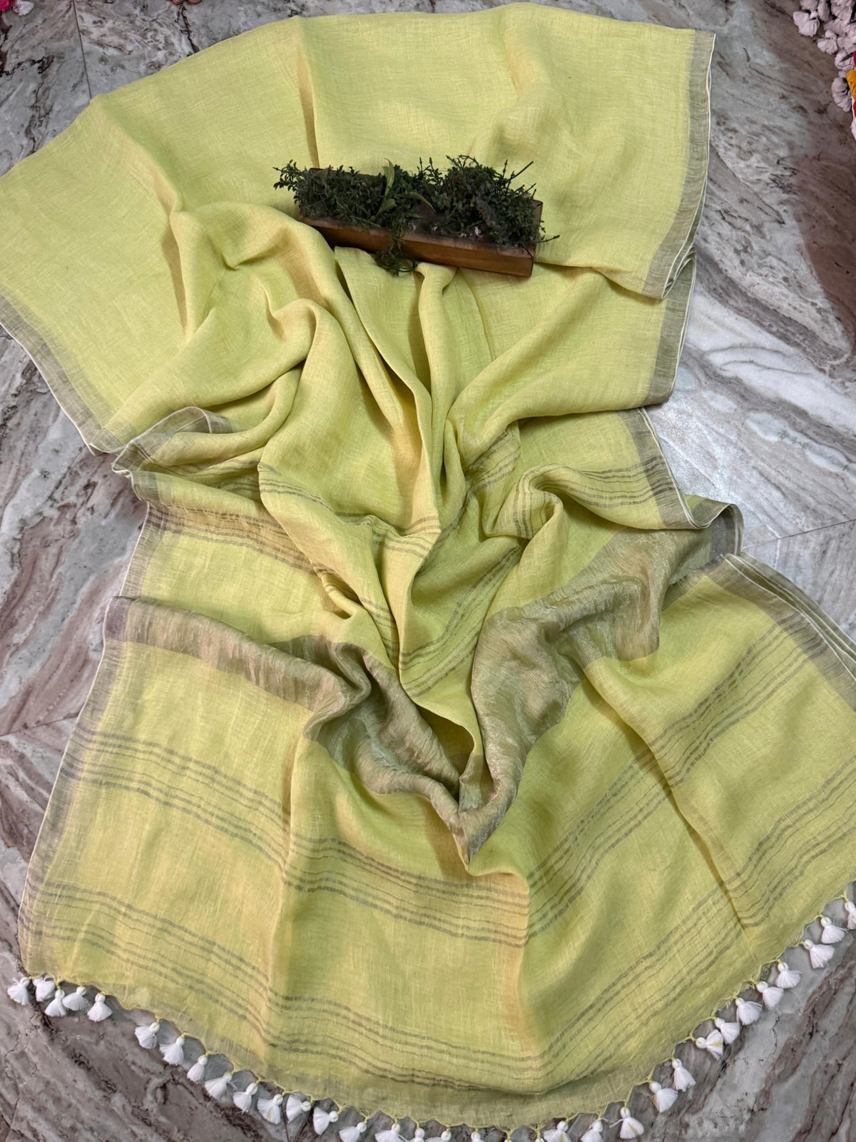 Pale yellow linen cotton handloom saree with subtle metallic striped pallu and white tassels